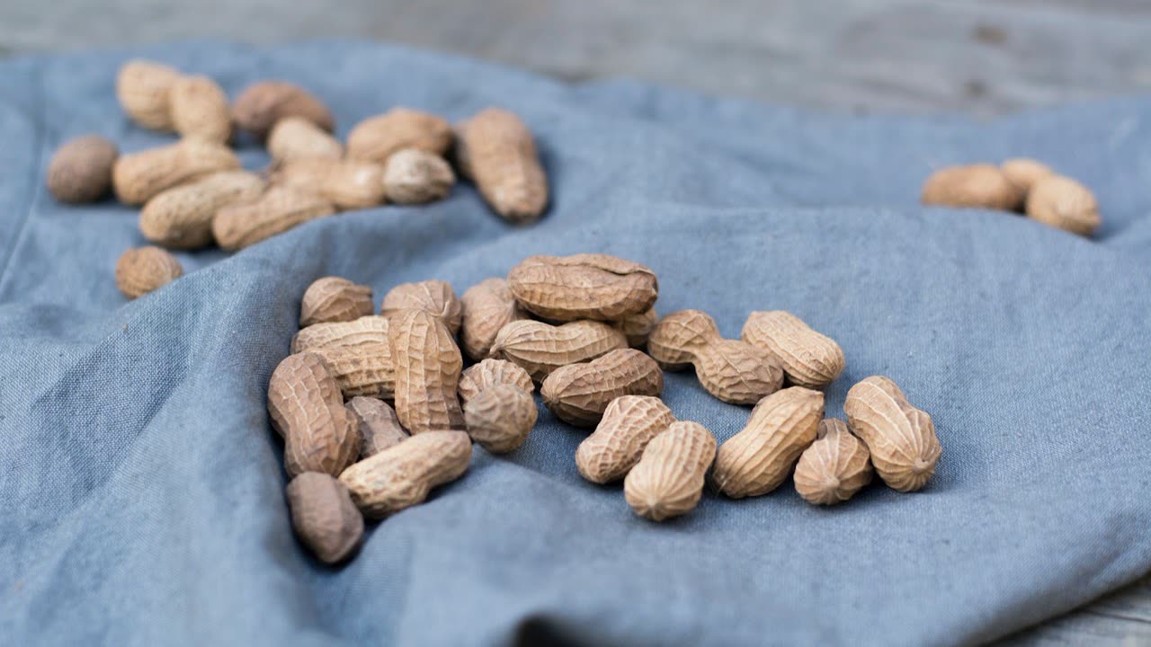 In-shell peanuts resting on a blue linen cloth