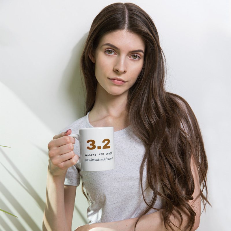 White mug reading 3.2 gallons per ounce, an almond could never.